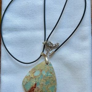 Polished stone pendant with black cord.